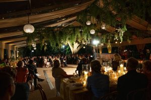 Elegant wedding reception tent illuminated at night in the New Orleans Museum of Art Sculpture Garden.