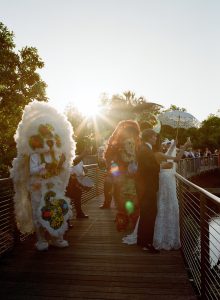 Bride and groom celebrating during a New Orleans second line in beautiful light at the NOMA Sculpture Garden.