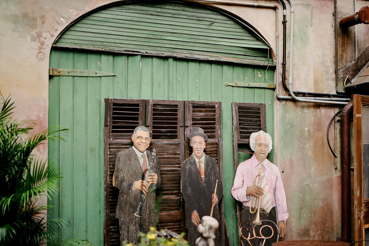 wooden cutouts of musicians set against a green, arched door