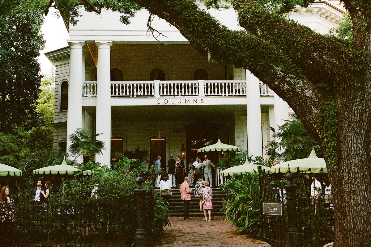 wedding guests mingling on the porch of the Columns Hotel wedding venue in New Orleans