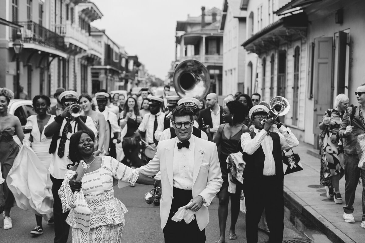 wedding party with a brass band marching in a second line parade in New Orleans