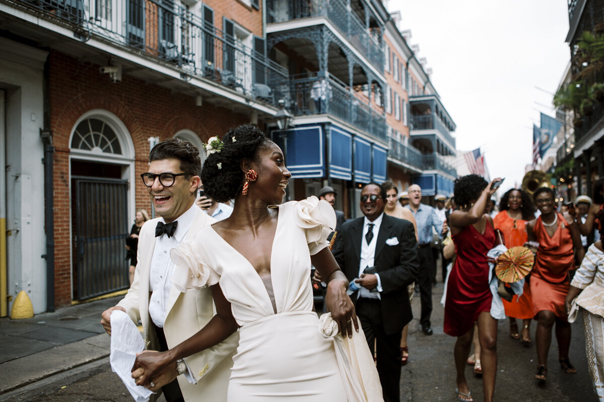 couple and their wedding guests taking part in a second line parade, following their wedding in New Orleans