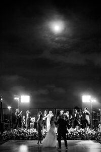 Wedding guests dancing under the moonlight during an outdoor reception at the NOMA Sculpture Garden in New Orleans.