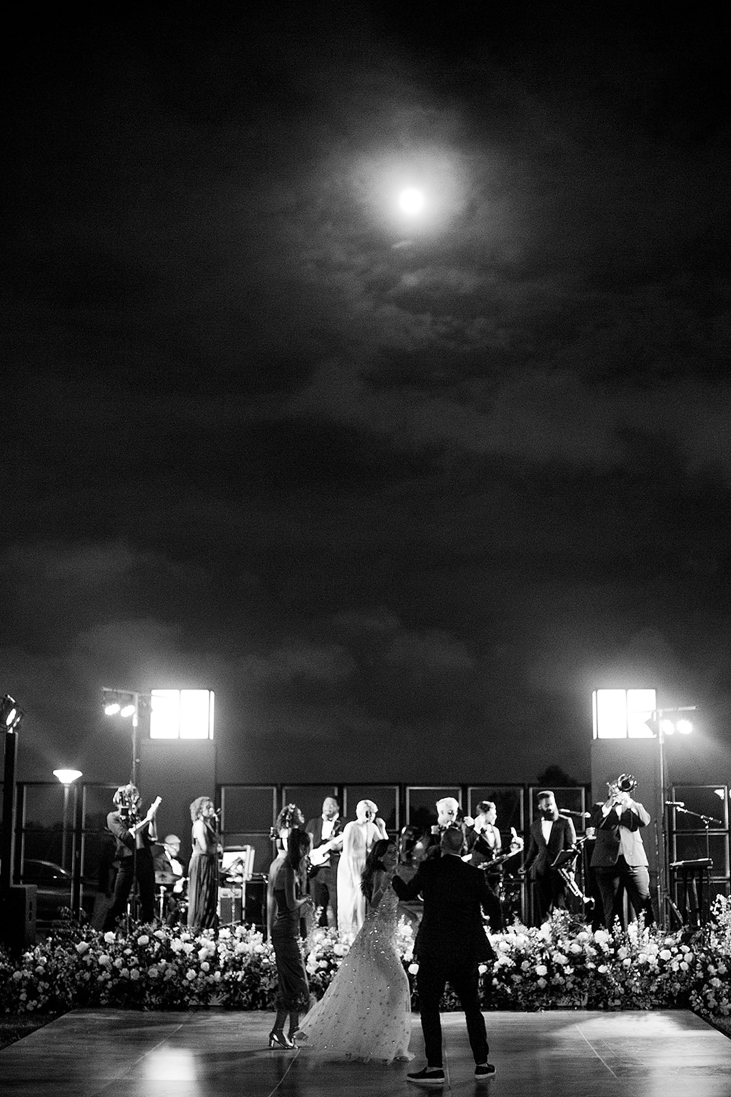 Wedding guests dancing under the moonlight during an outdoor reception at the NOMA Sculpture Garden in New Orleans.